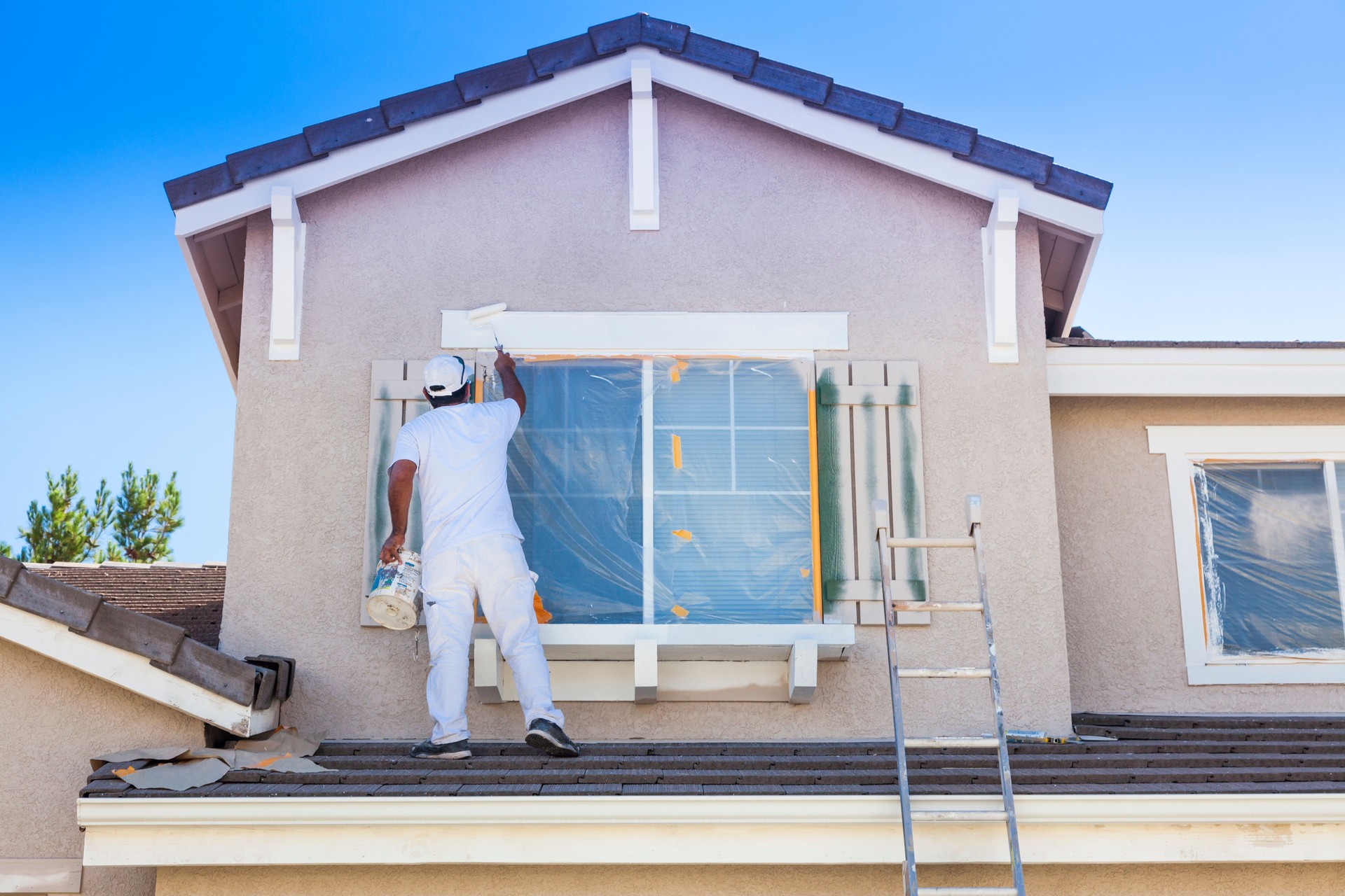 House Painter Painting the Trim And Shutters of Home